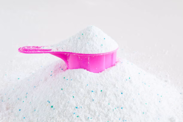 White cleaning detergent powder with a pink measuring scoop